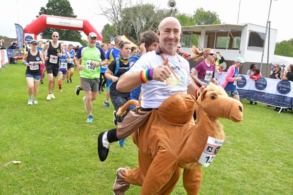 Runner dressed in Camel Costume smiling at the camera with a thumbs up