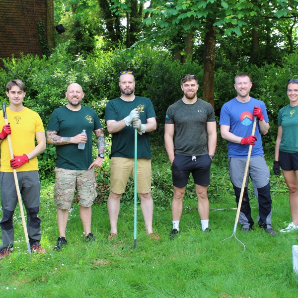Volunteer group stood in a row, holding gardening tools