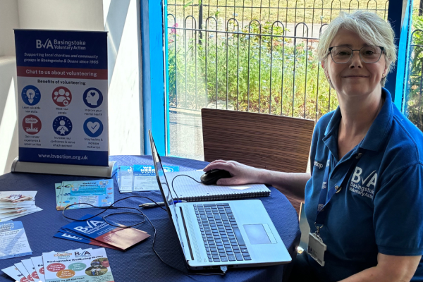BVA Staff member sat at table smiling at a Community Volunteer Hub