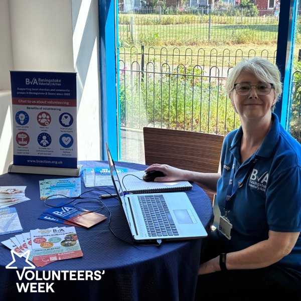 BVA Staff member sat at table smiling at a Community Volunteer Hub